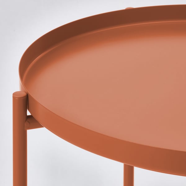 Rust-colored round tray table. Crafted from durable, easy-to-clean steel. Sturdy design with a smooth, glossy finish.