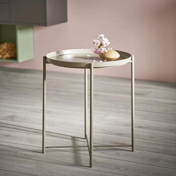 Modern round side table, mint-colored, metal frame and tray, minimalist design, holds small flowers and sphere.