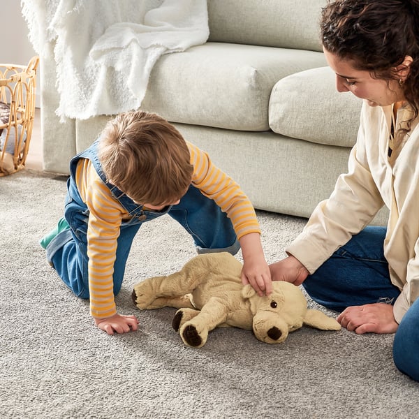 Children play with soft toy on floor, embracing comfort and companionship.