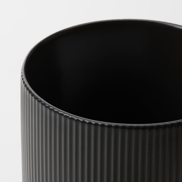 Black vase with vertical grooves on white background.