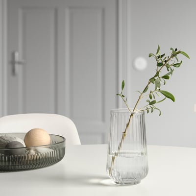Glass vase with green stem, black tray with spheres.