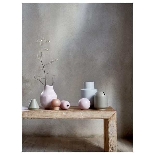 Colourful, modern decorative vases on wooden table against grey wall.