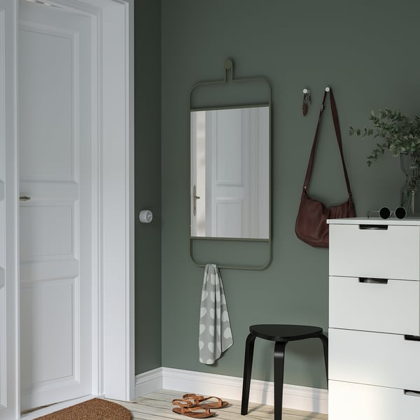 Green GRANVÅG mirror in hallway, reflects door, with hooks. Nearby: white dresser, bag, stool, polka dot towel.