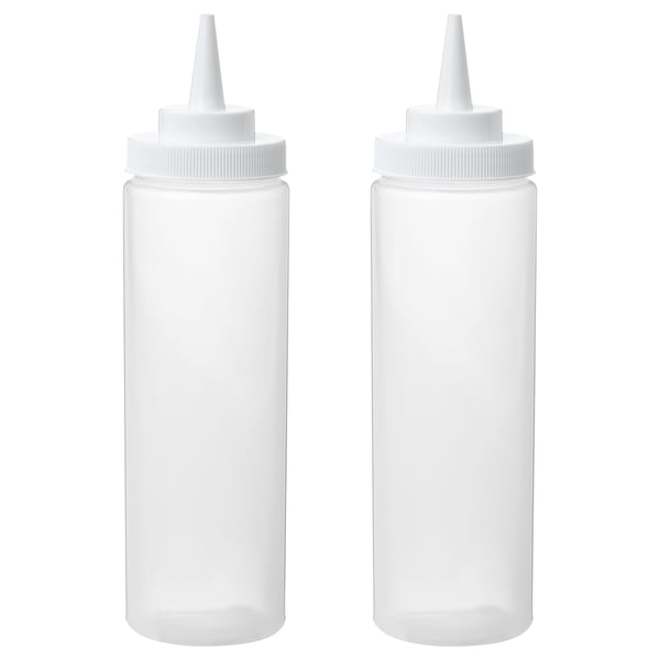 Two white squeeze bottles, empty, standing upright with caps on.