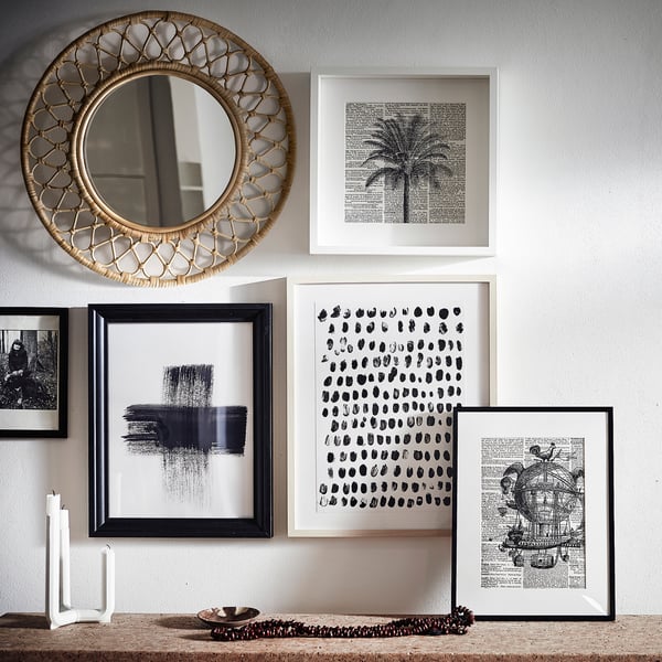 Wall display GRINSBOL rattan mirror surrounded by black-and-white framed art, creating a vibrant, textured composition.