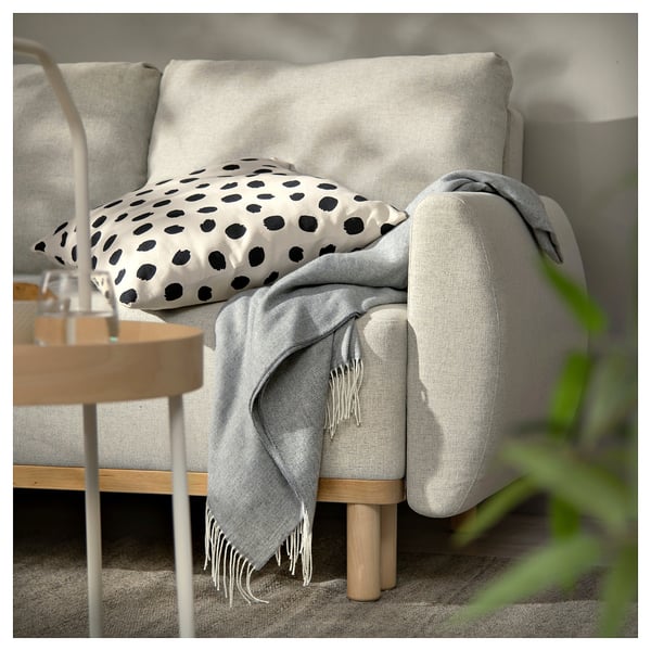 Neutral living room with GRUNNARP sofa-bed in grey fabric, black dotted pillow, and wooden side table.
