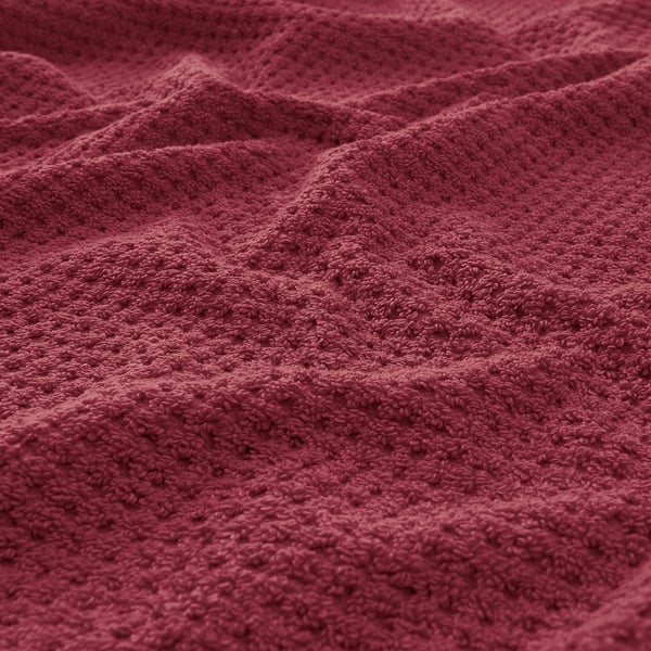 Soft, plush red towel made of 100% cotton, showcasing intricate weave pattern.