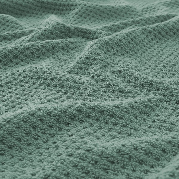 A close-up of a soft, textured, green terry towel showcasing its plush, absorbent quality.