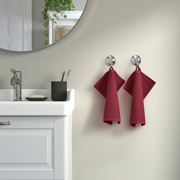 Bathroom with sink, faucet, mirror, & 2 burgundy towels on rings, larger than toothbrush holder.