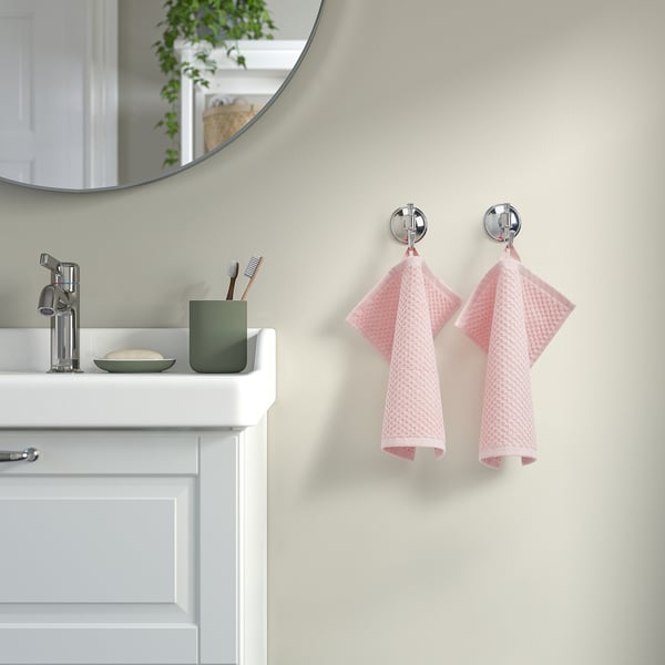 Bathroom with pink GULVIAL towels on chrome hooks by sink.