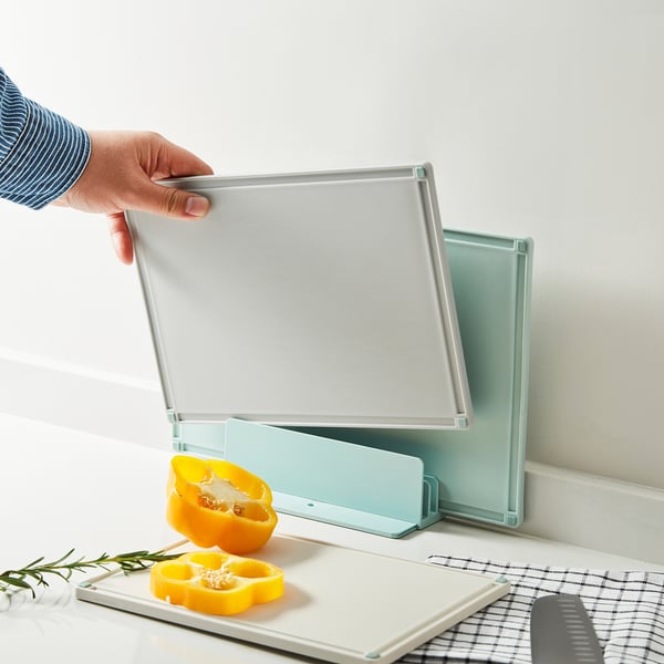 Hand holding GUMMIHAJ chopping boards. Assorted sizes/colors, non-slip, juices grooves.