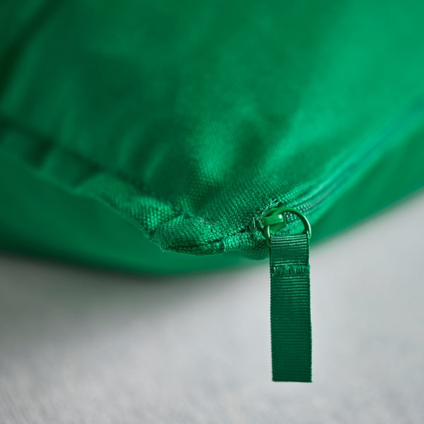 Green cushion cover with a durable zip, attached by a sturdy handle, showcasing high-quality recycled cotton fabric.