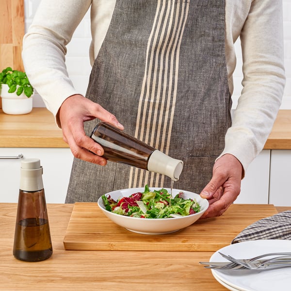 Pouring oil on salad from bottle.