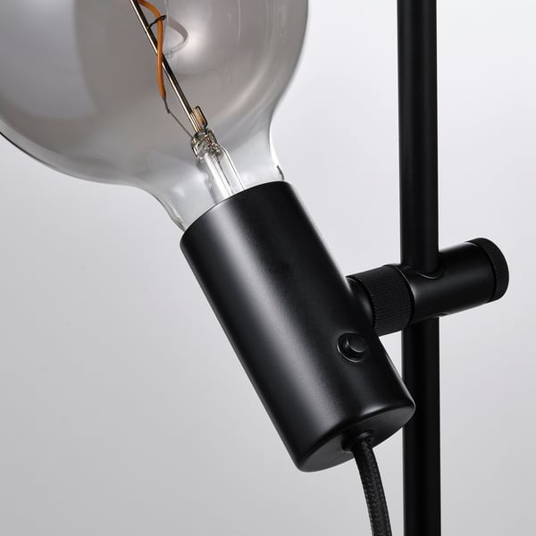 Close-up of modern lamp with large bulb, sleek black holder, and adjustable joint.