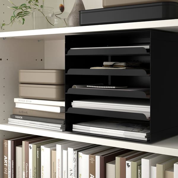 Bookshelf with letter trays and stacks of books under lighting.