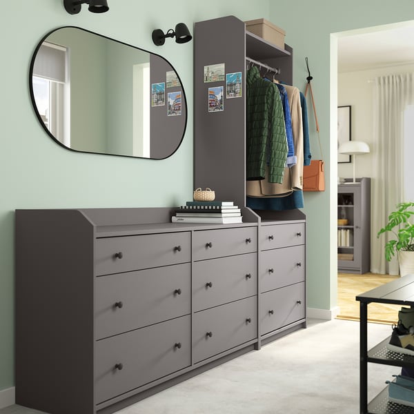 Modern bedroom with HAUGA grey dressers, mirror, and wardrobe. Clothes and bags are neatly organised; light blue walls.