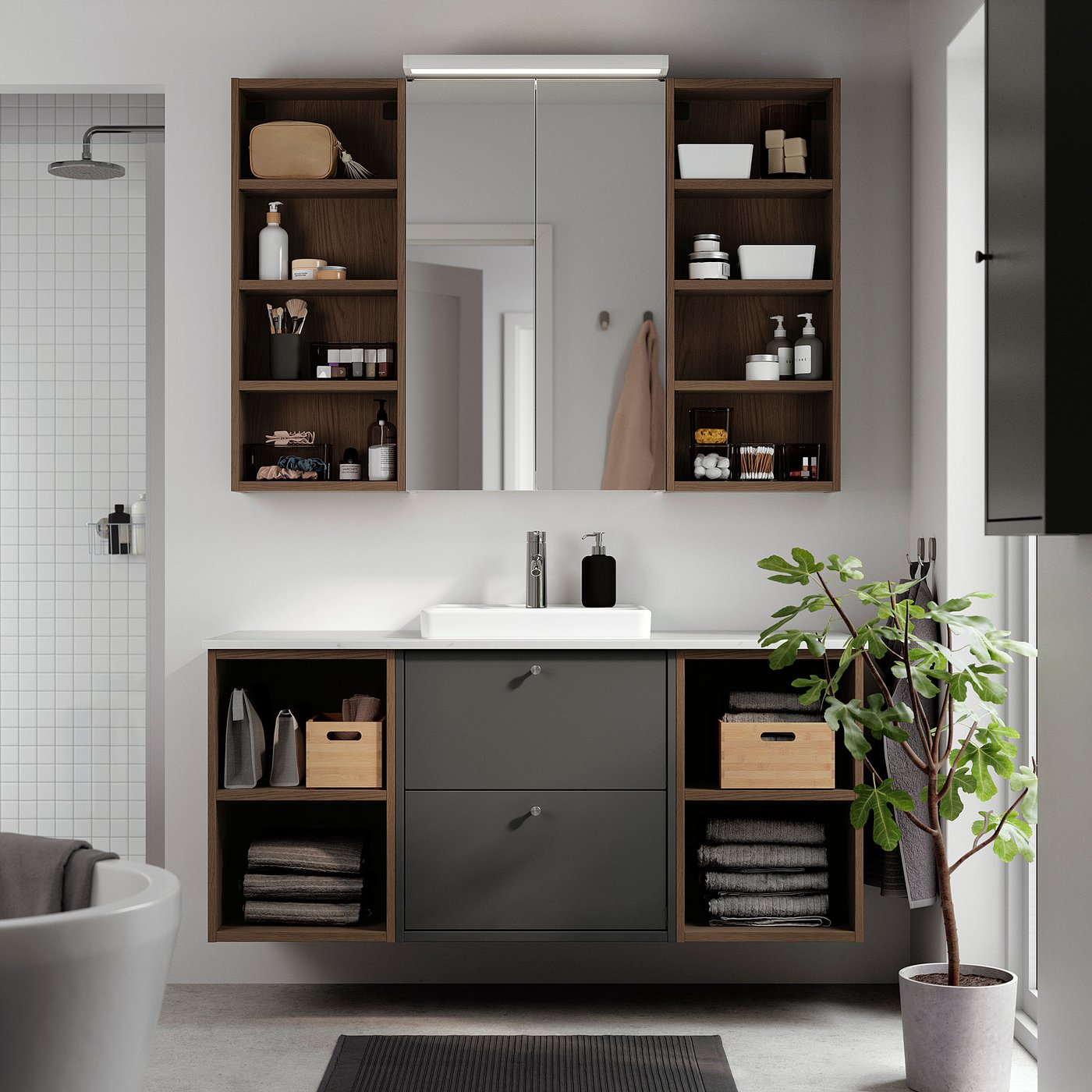 Modern bathroom with dark grey HAVBÄCK vanity, mirror, and open shelves against a white tiled wall. Includes sink and storage.