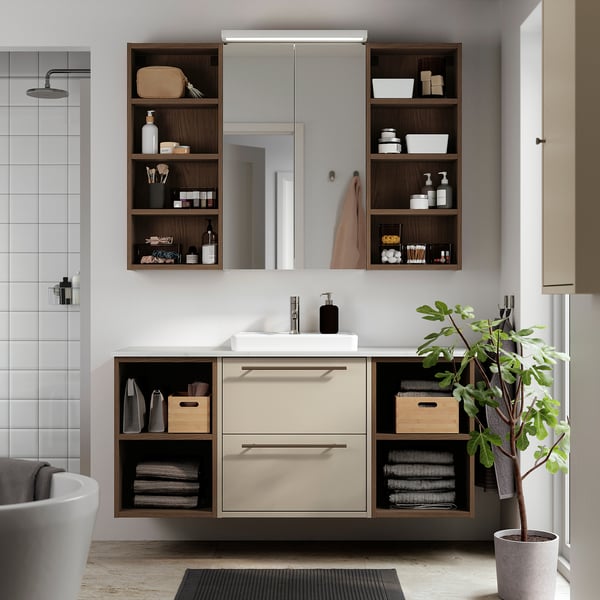Modern bathroom with beige HAVBÄCK vanity. Drawers, shelves, and a white basin. Decorated with towels and plants.