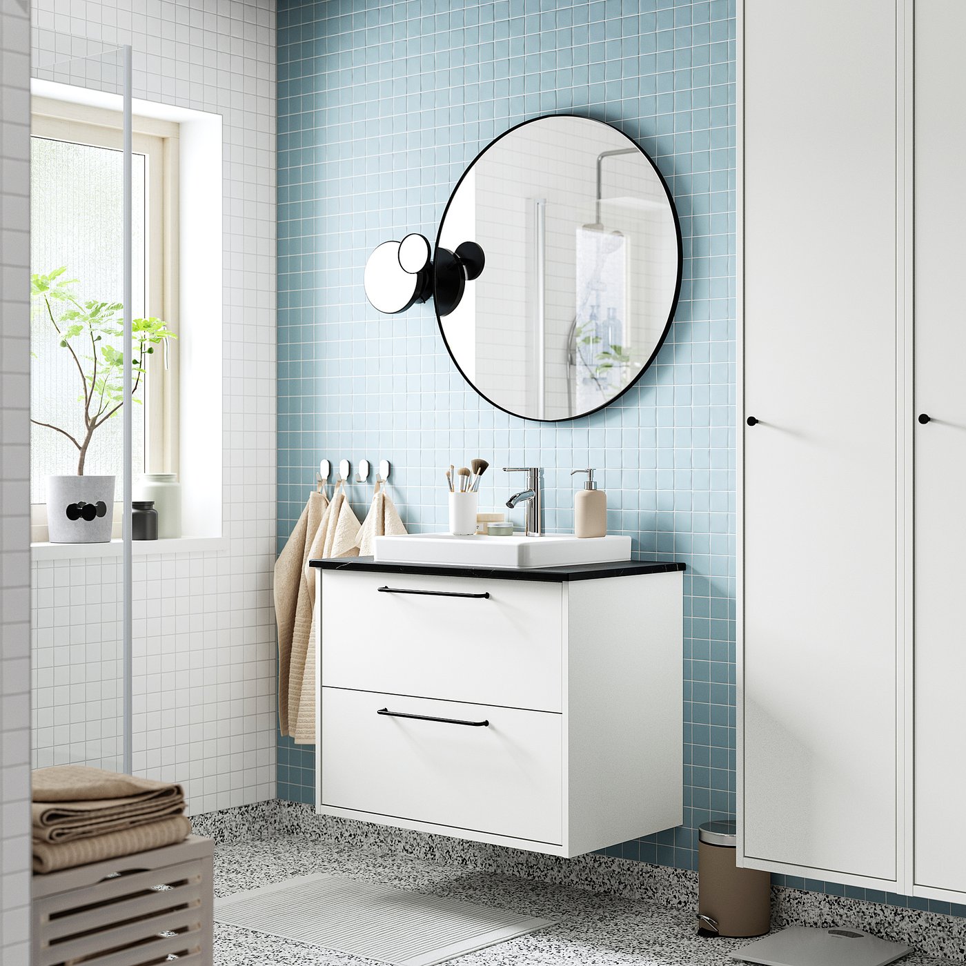 Modern white bathroom with HAVBÄCK washstand, large round mirror, minimalist lights, plant, towels, blue tiles.