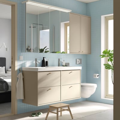Space-saving cabinet with mirror doors in a blue-tiled bathroom.