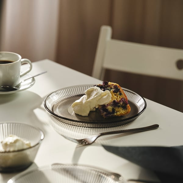 Cake with whipped cream, coffee, and fork on a wooden table.