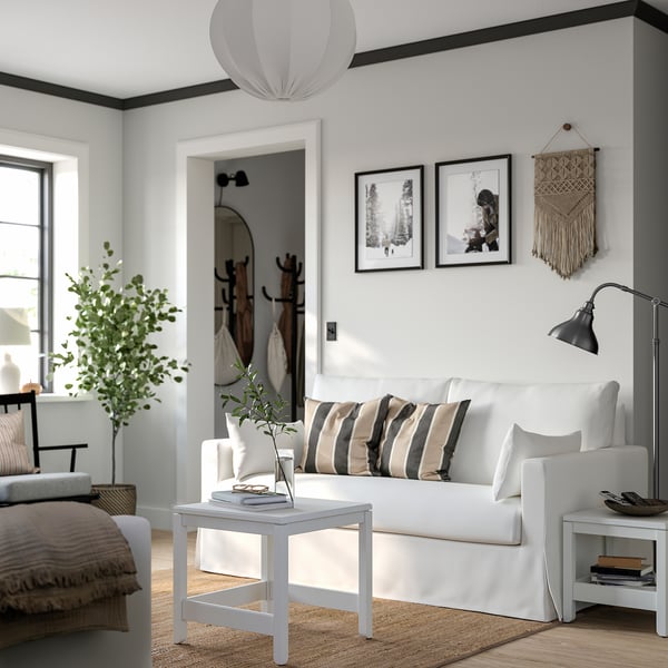 Modern living room with HAVSTA coffee tables, white sofa, boho decor, and floor lamp.