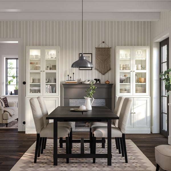 Modern dining room with HAVSTA glass and wooden cabinets, beige chairs, dark table, patterned rug, and pendant light.