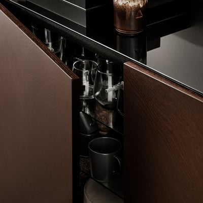 Dark wood cabinet with shelves holding black mugs and clear glasses.