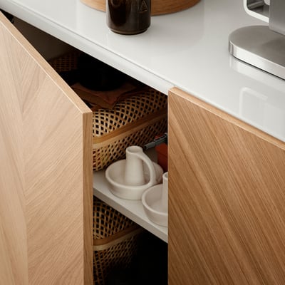 Wooden kitchen drawer with wicker baskets and a mortar and pestle. Light wood, organised, modern style.