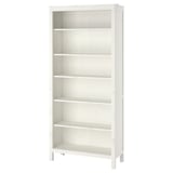 A white HEMNES bookshelf made of solid pine wood, featuring adjustable shelves and a natural finish.