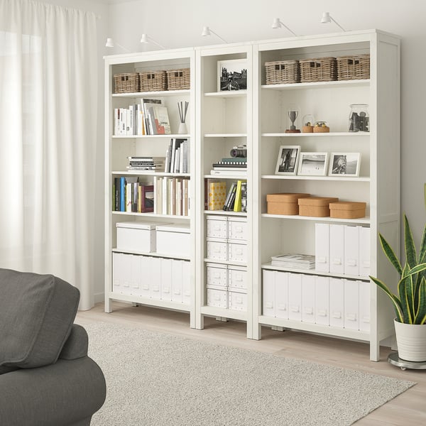 HEMNES bookcase in living room with pine, adjustable shelves, near grey sofa.