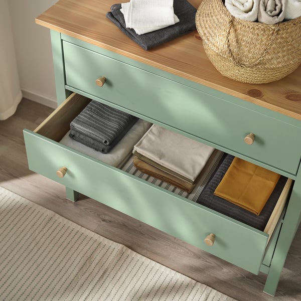 Open green chest of drawers with folded clothes inside. Drawer organiser visible.