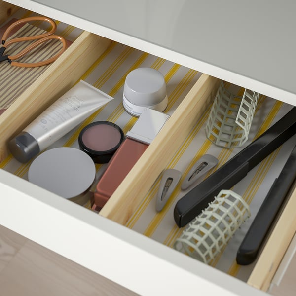Open drawer of HEMNES dressing table showing cosmetics, tools, and organisers, indicating practical storage for beauty items.