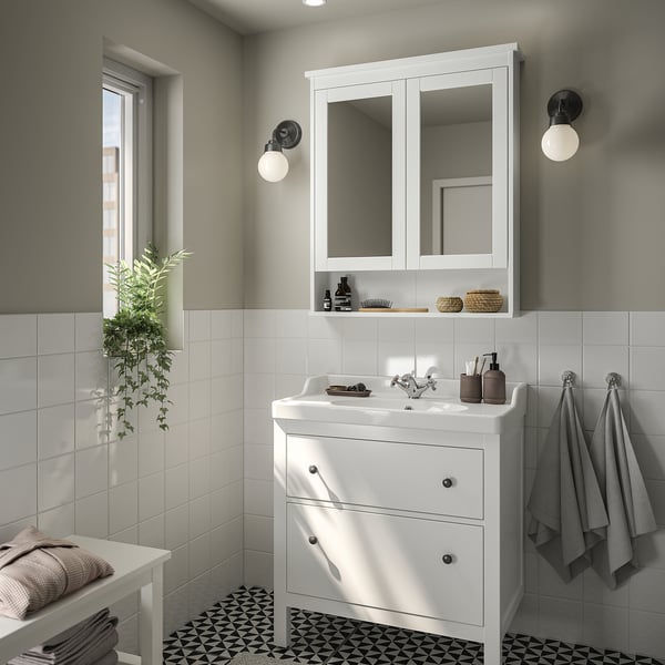 White bathroom with mirror cabinet, sink, & towels.