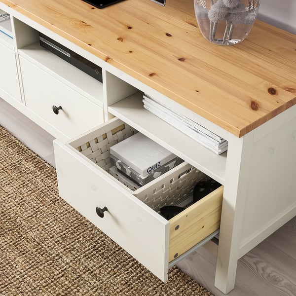A white-painted wooden tv stand with a pine top, featuring open and closed storage, including a drawer with organised compartments.