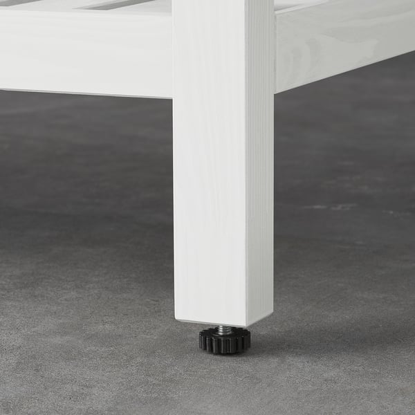 Close-up of white table leg with adjustable black foot, showcasing sturdy build and stability.