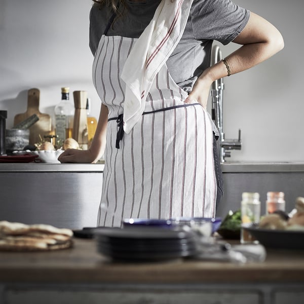Person in kitchen with striped apron, counter with items.