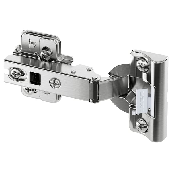 A silver HJÄLPA hinge with a built-in damper for soft door closure. Its metallic with a sleek design and star-shaped screws.