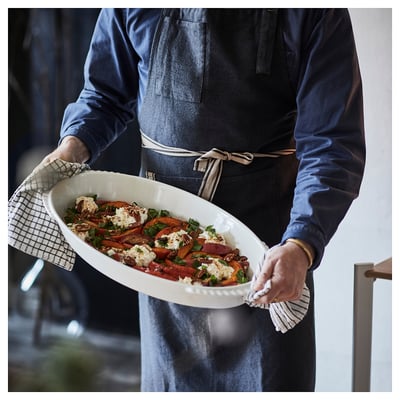 Person holding a large oven dish with roasted vegetables, ready to serve.