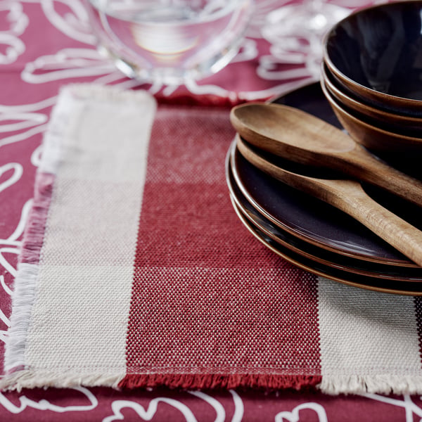 Close-up of a sustainable, woven placemat in warm autumn colours, neatly framed by glassware and wooden utensils.