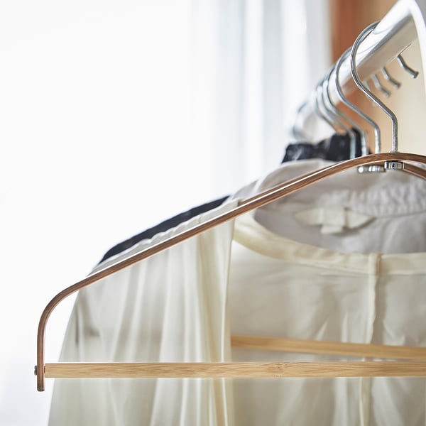 Wooden hanger with curved shape, holding white fabric. Modern, space-saving design with metal hook.