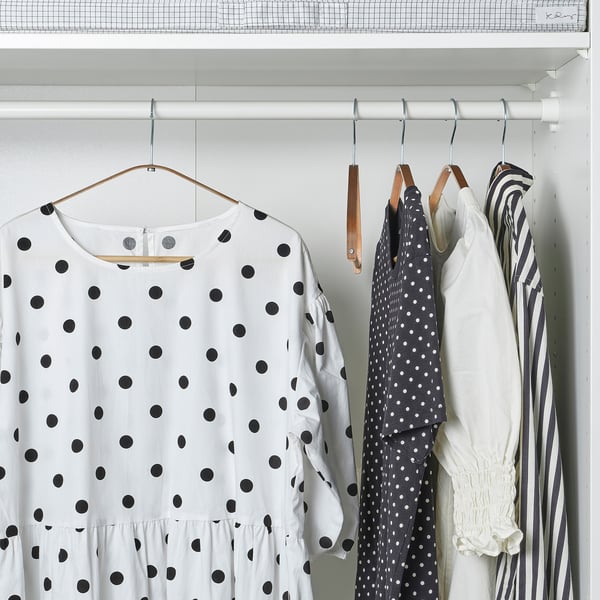 Closet with polka-dotted white shirt on hanger, next to two more shirts.