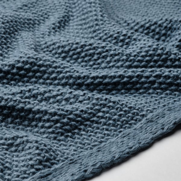 Close-up of soft, blue-grey knitted blanket, showcasing intricate textures and high-quality craftsmanship.