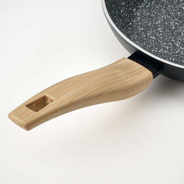 Close-up of a high-quality non-stick frying pan with a wooden handle on a white surface.