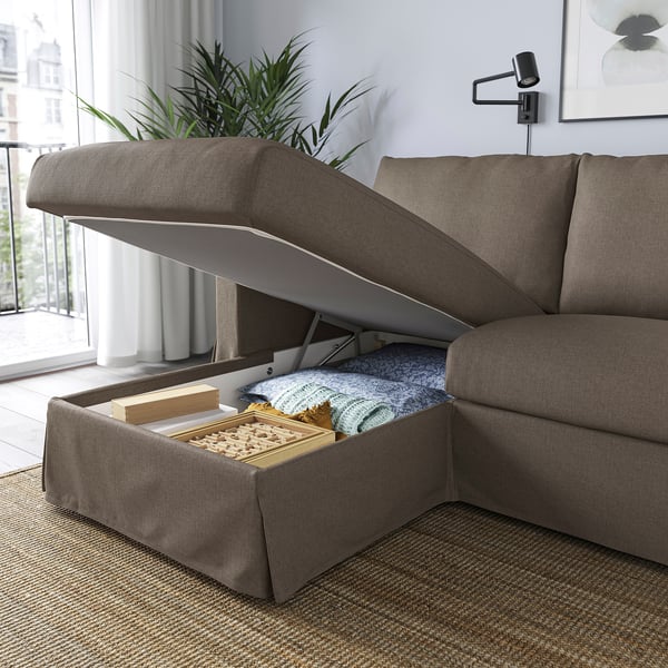 Modern sofa with storage. Chaise longue lid open, revealing blankets and games inside.
