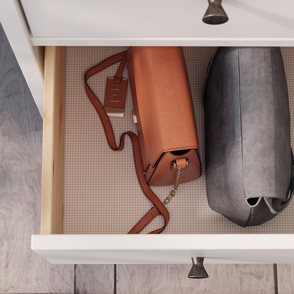 Brown leather purse with long strap in drawer beside black bag.