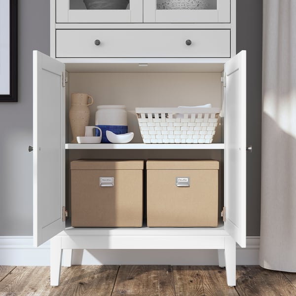 White wooden cabinet with open doors, shelves, and storage boxes.
