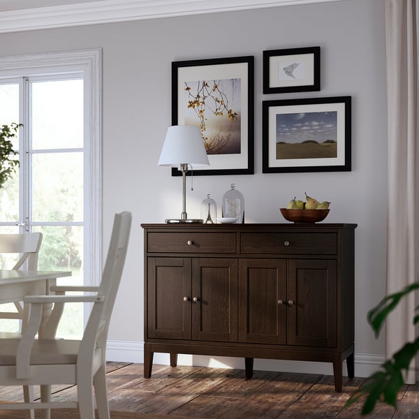 Modern dining area with IDANÄS dark wood sideboard, white lamp, and framed artwork.