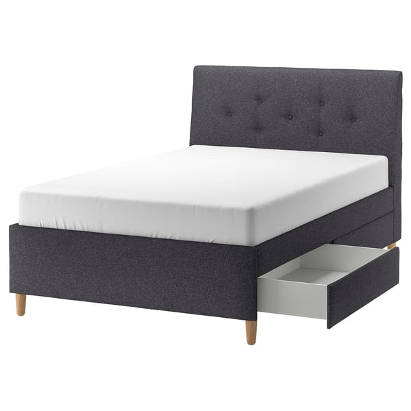 IDANÄS dark grey upholstered bed with sloped headboard, wooden legs, and two drawers for storage.