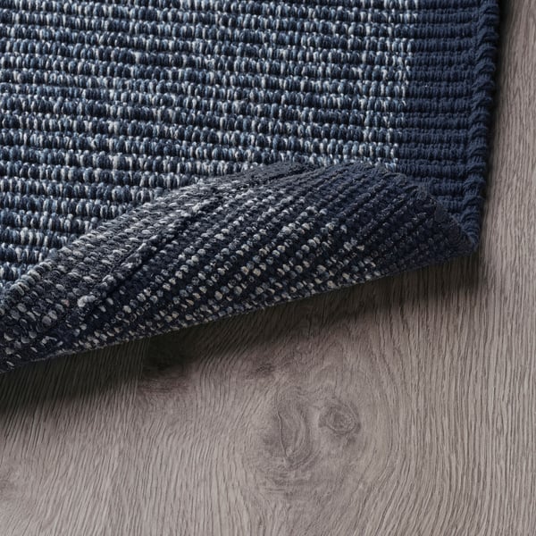Dark blue cotton doormat with white specks, folded on light wooden floor.